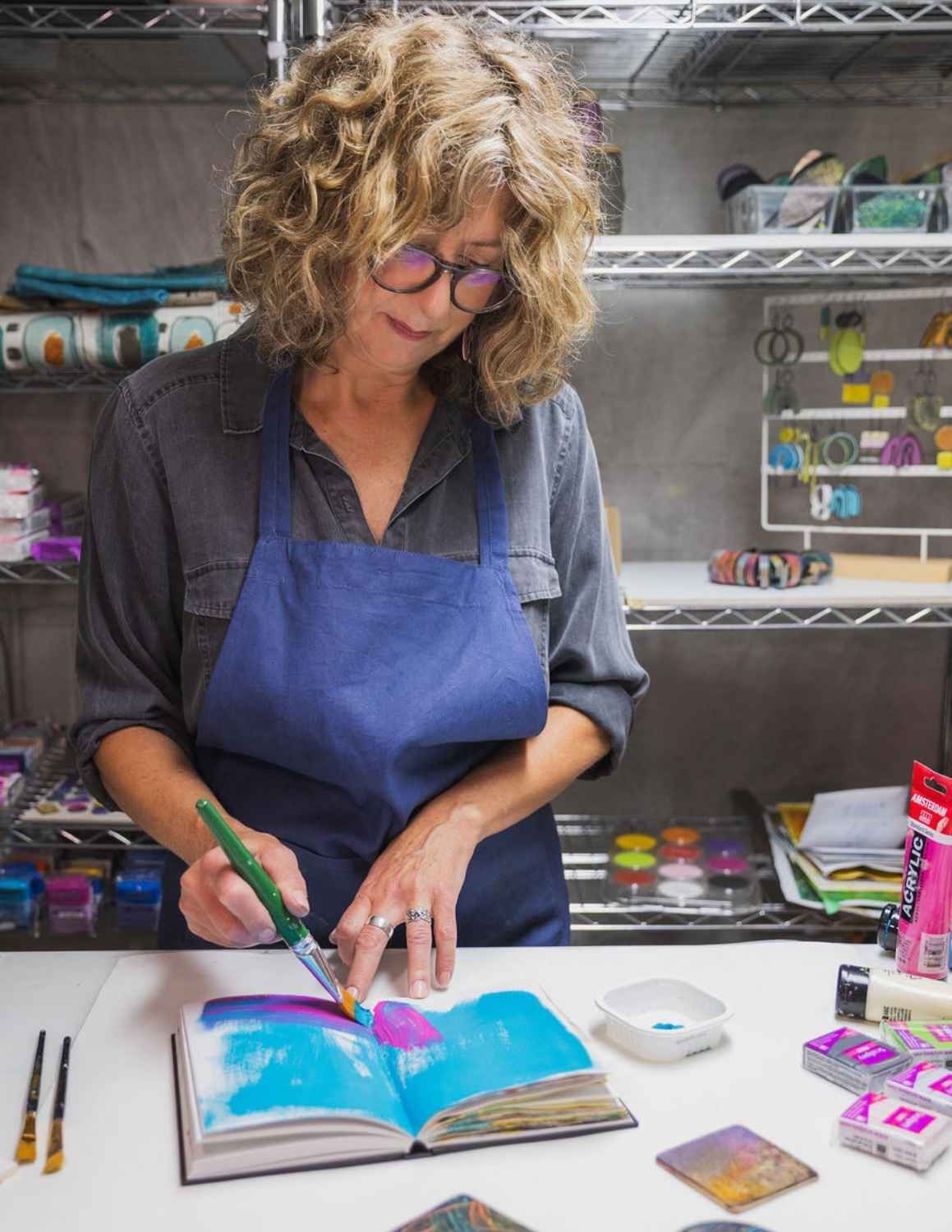 Artist in her studio adding paint to her sketchbook