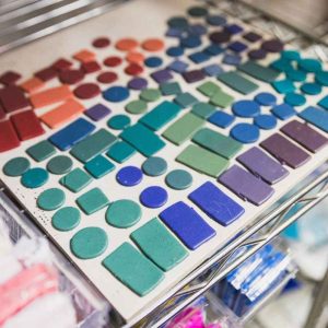 many colourful pieces of polymer clay on a ceramic tile ready to bake